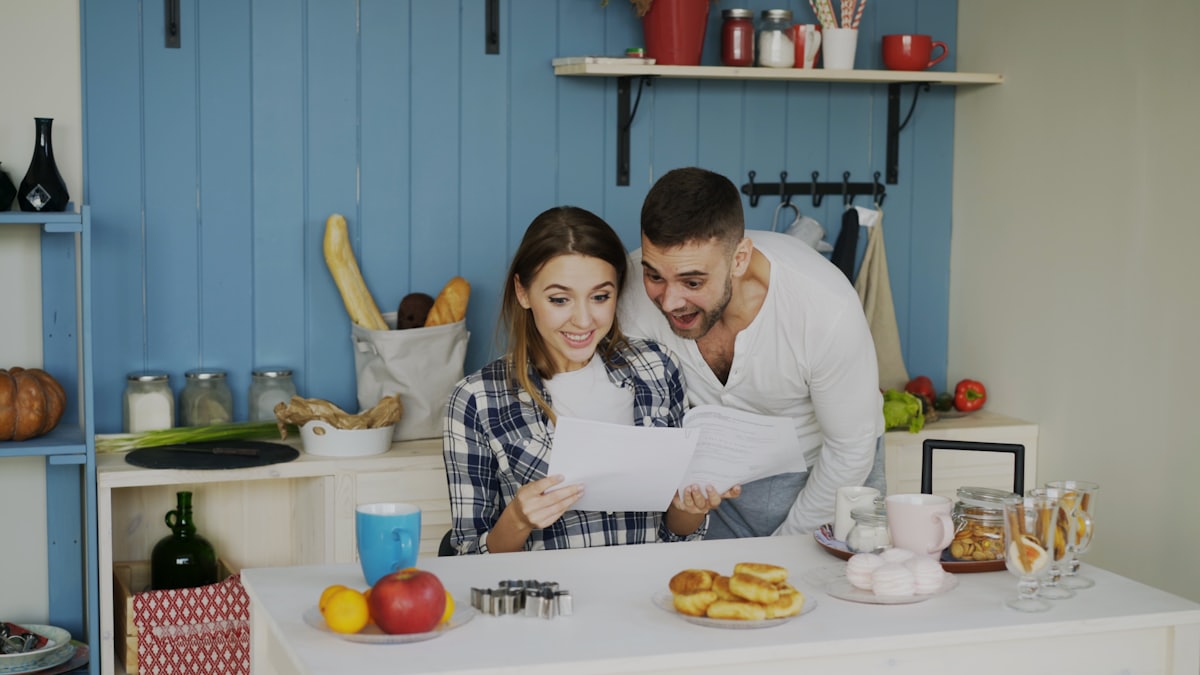 Koppel bekijkt samen papieren in een lichte keuken